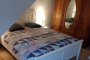 A bedroom with a bed, a wooden wardrobe, and a mirror. - Holiday apartment with 2 bedrooms (Nottfeld)