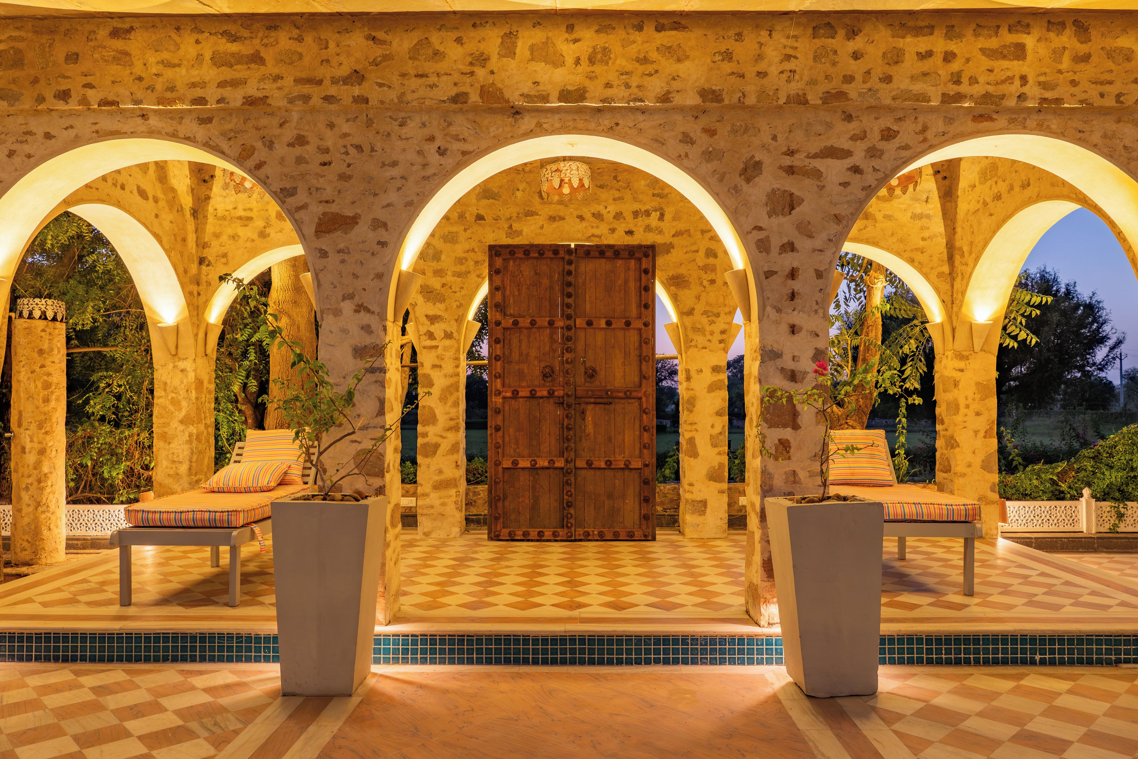 A courtyard with a checkered floor, stone walls, and a wooden door.