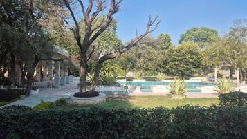 A courtyard with a swimming pool, stone columns, and lush greenery.
