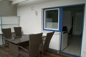A dining area with a table and chairs, a window with blinds, and a door leading to another room. - Holiday apartment with 2 bedrooms (Sierksdorf)