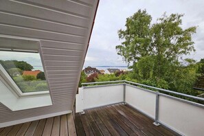A balcony with a view of a tree and houses in the distance. - Holiday apartment with 2 bedrooms (Sierksdorf)