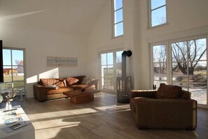 Ein geräumiges Wohnzimmer mit einem braunen Ledersofa, einem Couchtisch und einem Kamin.