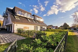 A two-story house with a sloped roof, a fenced garden, and a clear sky. - Holiday apartment with 1 bedroom (Zingst)