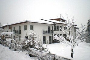 A two-story building with a balcony, a snow-covered roof, and a snow-covered ground. - Holiday apartment in Söll with swimming pool (Söll)