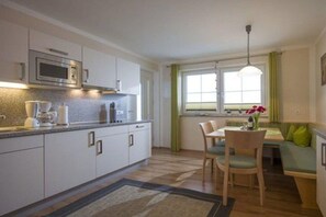 A compact kitchen with a microwave, coffee maker, and a dining area with chairs and a table. - Holiday apartment with 2 bedrooms (Hippach)