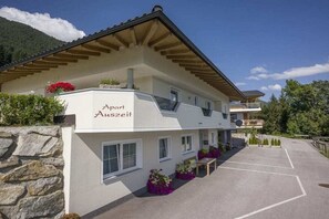 A two-story building with a stone facade, labeled 'Apart Auszeit,' featuring a covered outdoor seating area and a parking lot. - Holiday apartment with 2 bedrooms (Hippach)