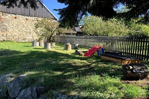A stone building, a wooden fence, and a red slide in a grassy area. - ||---------------------Valahof Barn----------------------|| (Milevsko)