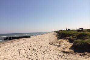 A sandy beach with a wooden fence and a grassy area with a bench. - Holiday apartment in Nieby with swimming pool (Nieby)