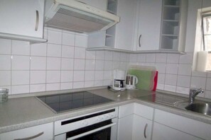 A kitchen with white cabinets, a built-in oven, a coffee maker, and a sink. - on the inland lake in the town center (Heiligenhafen)