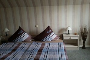 Ein Hotelzimmer mit gestreifter Wand, einem Bett mit gestreifter Bettdecke, zwei Nachttischen mit Lampen und dekorativen Elementen.