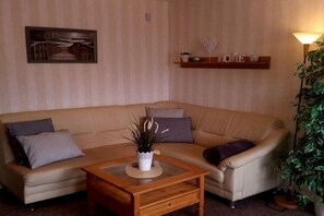 Ein Wohnzimmer mit einer Couch, einem Couchtisch, einer Wandregal mit Dekoration und einem gerahmten Bild.