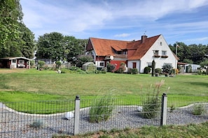 A two-story house with a red roof, surrounded by a well-maintained lawn and a metal fence. - Buhmann, Baltic Sea near Weißenhäuser Strand (Oldenburg in Holstein)