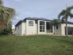 Ein Bungalow mit großer Garage, überdachter Veranda und gepflegtem Rasen.