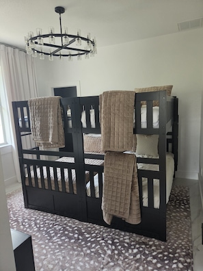 Ein Stockbett mit gesteppter Decke, einer Chandelierleuchtre und einem gemusterten Teppich.