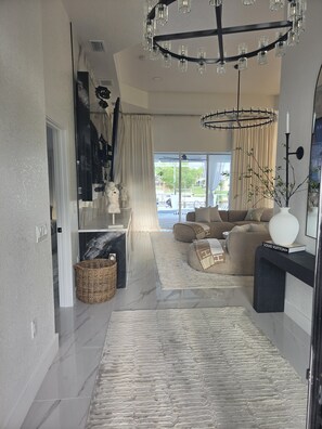 A modern living room with a marble floor, a large sofa, a fireplace, and a chandelier. - Royal Waterfront 5BR · Private Dock · Sleeps 16 (Port Charlotte)