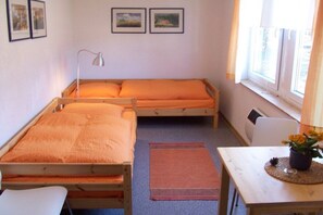 A room with two wooden beds, a desk, a chair, a lamp, and a window with curtains. - ||--------------under the linden tree----------------|| (Quitzdorf\/ OT Steinölsa)