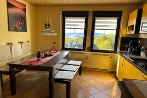 A kitchen with a dining table, bench seating, a view through the windows, and a radiator. - Holiday apartment with 2 bedrooms (Grünhain-Beierfeld)