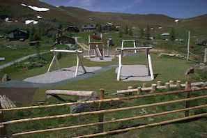 A rural setting with a playground, wooden fences, and houses in the background. - Holiday home with 1 bedroom (Patergassen)