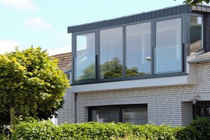 A modern two-story building with large windows and a brick facade. - Holiday home with 1 bedroom (Heiligenhafen)