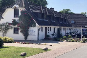 A white building with a sign reading 'Columbus' and a black car parked in front. - Holiday apartment with 2 bedrooms (Hohwacht)