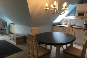 A dining area with a round table and four chairs, a chandelier, a radiator, and a small cabinet. - Holiday apartment with 2 bedrooms (Hohwacht)