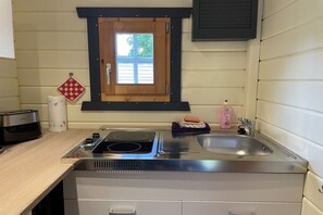 A kitchen with a built-in stove, a sink, and a window with a wooden frame. - Summer log cabin "An de Möhl" (Ostseebad Dierhagen \/OT Dändorf)