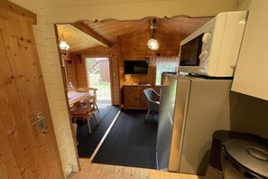 A wooden cabin interior with a kitchen area, a dining table, and a television. - Summer log cabin "An de Möhl" (Ostseebad Dierhagen \/OT Dändorf)