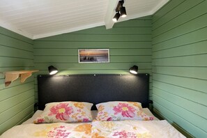 Une pièce comprenant un lit, une tête de lit, une étagère et un tableau accroché au mur.