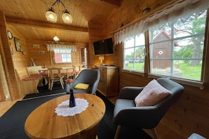 A cozy cabin interior with a dining area, a television, and a large window with a view of the outside. - Summer log cabin "An de Möhl" (Ostseebad Dierhagen \/OT Dändorf)