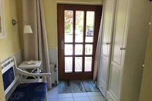A narrow hallway with a wooden door, a small table with a lamp, and a bench. - Holiday apartment with 1 bedroom (Hohwacht)