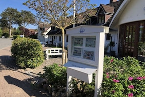 A white building with a signboard, a tree, and a pathway. - Holiday apartment with 1 bedroom (Hohwacht)