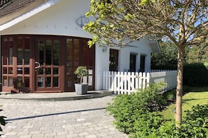 A building with a white exterior, a curved entrance, and a white picket fence. - Holiday apartment with 1 bedroom (Hohwacht)