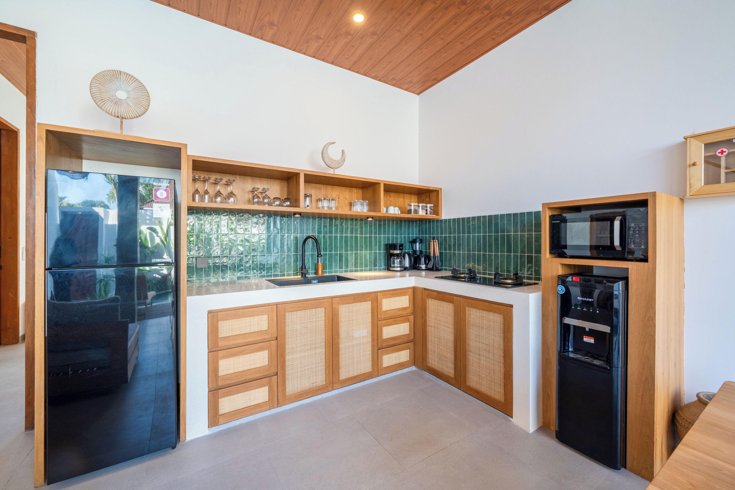 Cozinha moderna com armários de madeira, geladeira preta, micro-ondas e cafeteira.