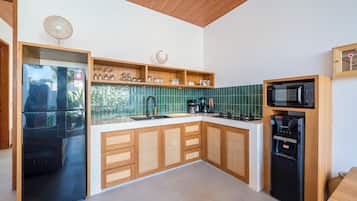 Cozinha moderna com armários de madeira, geladeira preta, micro-ondas e cafeteira.