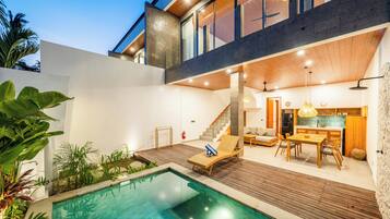 Una casa moderna con piscina, terraza de madera y zona de comedor.