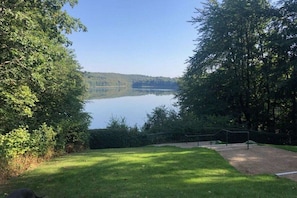 A lake surrounded by trees, a grassy area, and a fence. - Holiday apartment with 2 bedrooms (Hohwacht)