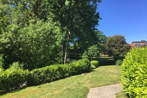 Un chemin pavé dans un jardin bien entretenu, avec une végétation luxuriante et un ciel bleu dégagé.