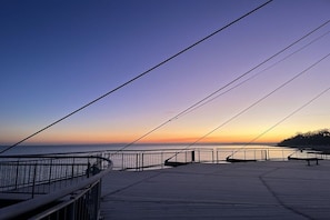 A waterfront promenade with a metal railing, benches, and a clear sky. - Holiday apartment with 2 bedrooms (Hohwacht)