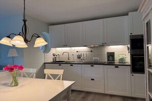 Une cuisine moderne avec des armoires blanches, un comptoir noir et un lustre.