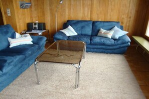 A living room with two blue sofas, a coffee table, and a small table with electronic devices. - Holiday apartment with 2 bedrooms (Beatenberg)