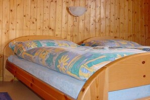 A wooden bed with a floral bedspread and a wall-mounted light fixture. - Holiday apartment with 2 bedrooms (Beatenberg)