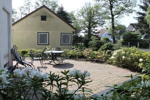 Ett hus med en stenlagd uteplats, ett bord och stolar.