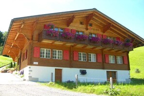 Un chalet traditionnel avec une façade en bois, des balcons ornés de jardinières et une enseigne indiquant la présence d’un restaurant.