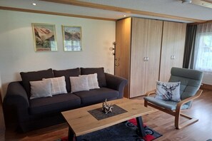 A modern living room with a sofa, a coffee table, and a chair. There are two framed pictures on the wall. - Holiday apartment with 2 bedrooms (Grindelwald)