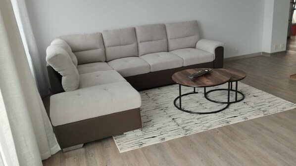 Ein Ecksofa mit Chaiselongue, einem Couchtisch und einem gemusterten Teppich in einem Raum mit Holzböden.