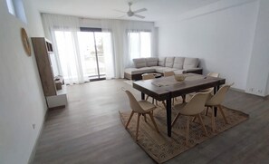 Ein moderner Wohnraum mit Essbereich, Sofa und Deckenventilator.