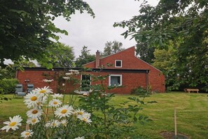 Ein rotes Backsteinhaus mit einer kleinen Veranda und einem Rasen.