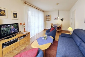 A living room with a television, sofa, coffee table, and dining area. - House "An der Düne" Apartment C-9 (Seebad Heringsdorf)
