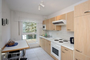 A compact kitchen with a dining area, a window with a view, and a built-in microwave. - House "An der Düne" Apartment C-9 (Seebad Heringsdorf)