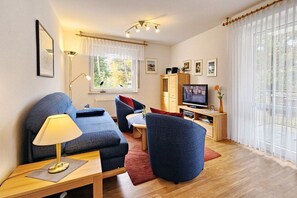 Uma sala de estar moderna com sofá, poltrona, televisão e um armário de madeira.